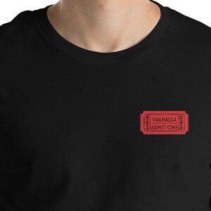 Op de afbeelding: Zwart T-shirt met een rood ticketontwerp met de tekst "Valhalla Admit One".