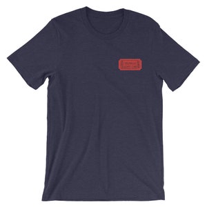 Op de afbeelding: Een marineblauw t-shirt met een rood ticketontwerp met de tekst "Valhalla Admit One".