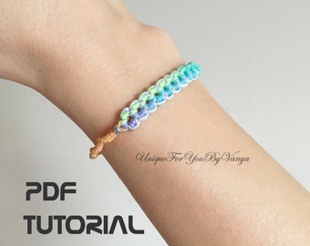 May include: A colorful friendship bracelet with a gradient of blue, green, and yellow colors. The bracelet is made with a knotting technique and has a simple, elegant design. The image includes the text "PDF TUTORIAL" and "Unique For You By Vanya".