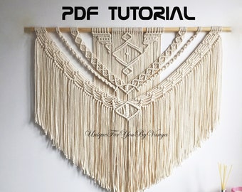 Peut inclure: Une suspension murale en macramé beige avec un motif géométrique et des franges. La suspension est fixée à une baguette en bois. Le texte "PDF TUTORIAL" et "Unique For You By Vanya" sont visibles sur l'image.