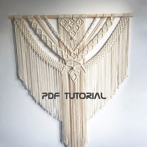 May include: A large, white macrame wall hanging with a geometric design. The hanging is made with thick cotton cord and has a wooden dowel at the top. The text "PDF TUTORIAL" is printed in black at the bottom of the hanging.