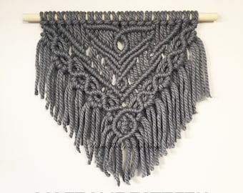 May include: Gray macrame wall hanging with a geometric pattern and fringe. The hanging is attached to a wooden dowel. "PDF TUTORIAL" and "MACRAME PATTERN" are written in black text at the top and bottom of the image.
