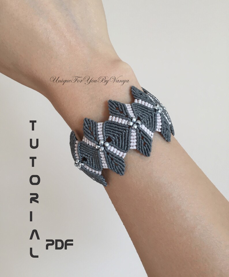May include: Grey and pink macrame bracelet with silver beads. The bracelet is on a person's wrist. The text "TUTORIAL PDF" is on the left side of the image.