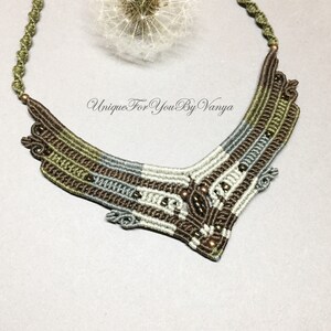 May include: A brown, green and grey macrame necklace with a geometric design and copper beads. The necklace is made with a variety of cords and beads, creating a unique and intricate pattern.