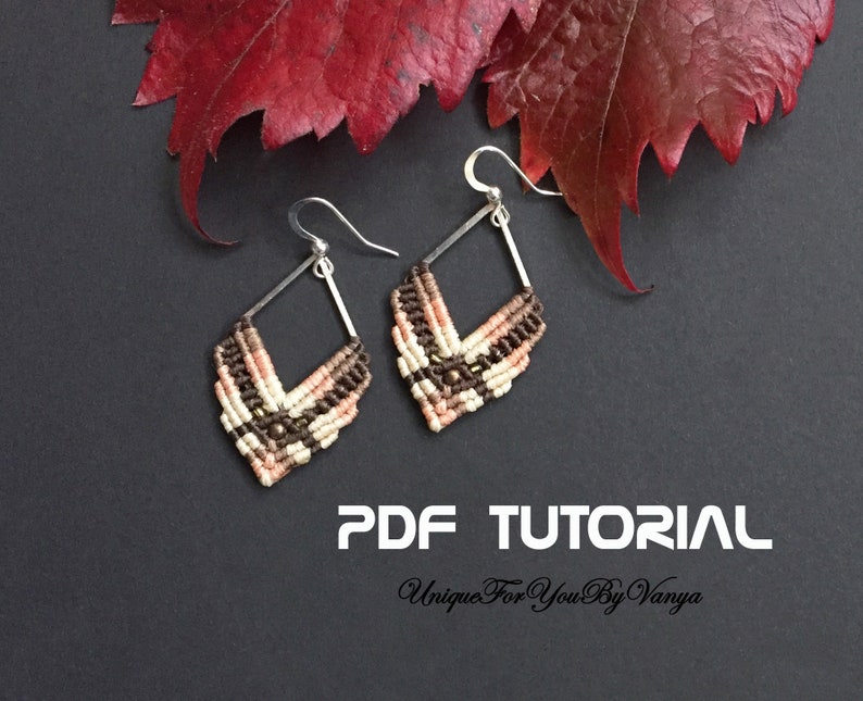 K&ouml;nnte beinhalten: Ein Paar handgefertigte Makramee-Ohrringe in Diamantenform. Die Ohrringe haben beige, braune und pfirsichfarbene F&auml;den und kleine Perlen. Sie h&auml;ngen an silberfarbenen Haken. Der Hintergrund ist dunkelgrau mit roten Bl&auml;ttern. Text: PDF TUTORIAL, Unique For You By Vanya.