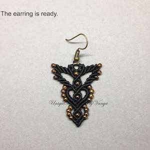 Pu&ograve; includere: Orecchino in macram&egrave; nero e oro con un design geometrico e una chiusura a gancio. L'orecchino &egrave; etichettato "Unique by Vanya".