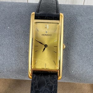 Vintage and Very Rare Movado 87.E4.485 Gold Tank Champagne Dial Roman Numerals 18K Gold Plated Case Black Strap