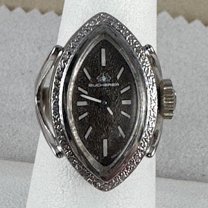Vintage Bucherer Marcasite Ring Watch Swiss Made Rhodium Plated is 6.5 sized. Case is 7/8 by 9/16 inch wide Diamond or Marquise Ring Shape