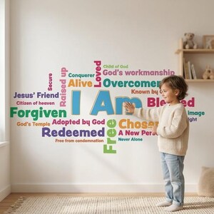 Op de afbeelding: Een muursticker met de woorden "I Am" in blauw, omringd door andere woorden in verschillende kleuren. De woorden zijn onder meer "Forgiven", "Redeemed" en "Chosen". Een kind staat in de buurt van de sticker.