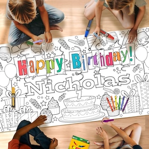 May include: A large, white coloring sheet with the words "Happy Birthday Nicholas!" is being colored by children. The sheet features birthday-themed illustrations like cake, cupcakes, and gifts. A box of 10 markers is also visible.