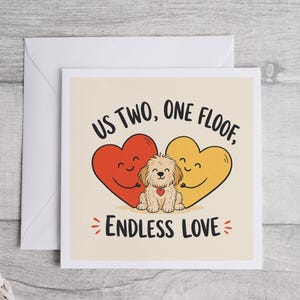 May include: A square greeting card with a cream background featuring a red heart and a yellow heart hugging a small, fluffy, light brown dog. The text reads US TWO, ONE FLOOF, ENDLESS LOVE. A matching white envelope is positioned behind the card.