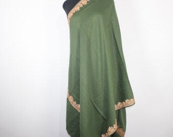 May include: A green shawl with gold embroidery around the edges. The shawl is draped over a mannequin.