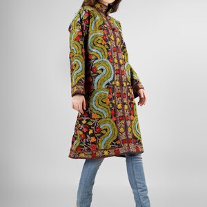 May include: A long black embroidered coat with a floral and paisley design in shades of red, green, blue, and yellow. The coat has a high collar and a button closure.