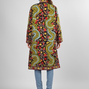 May include: A long black embroidered coat with a floral and paisley pattern in shades of red, green, blue, and yellow. The coat has a mandarin collar and long sleeves.