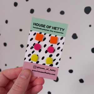May include: A set of six polymer clay earrings in yellow, pink and orange. The earrings are in the shape of squares and circles. The earrings are displayed on a card with the text "HOUSE OF HETTY handmade polymer clay accessories @house_of_hetty www.houseofhetty.com"