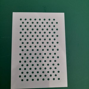 May include: White plastic stencil with a repeating pattern of small circles.