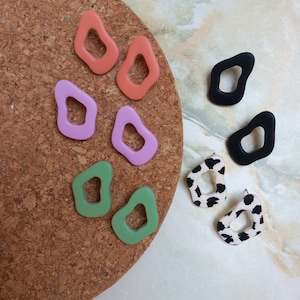 May include: Assortment of colorful and patterned earrings in various shapes. The earrings are made of polymer clay and feature unique designs, including abstract shapes, animal prints, and solid colors.