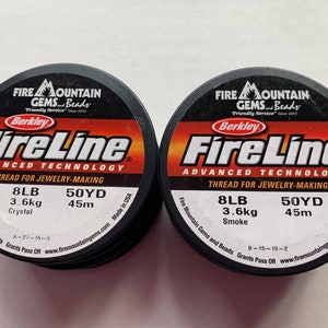 May include: Two spools of black FireLine Advanced Technology thread for jewelry making. Each spool is labeled with 8lb (3.6kg) and 50yd (45m). One spool is labeled "Crystal" and the other is labeled "Smoke".
