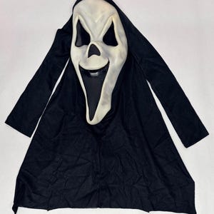 May include: A Scream mask with a white face and black eye sockets, nose, and mouth. The mask is attached to a black hooded robe. The mask has a ghostly appearance, with a wide, open mouth and a slightly curved smile.