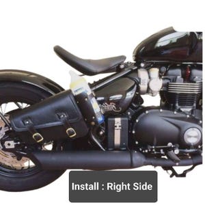 May include: Black leather motorcycle saddlebag with a buckle closure. The saddlebag is attached to the right side of a black motorcycle. The text "Install: Right Side" is visible in the image.