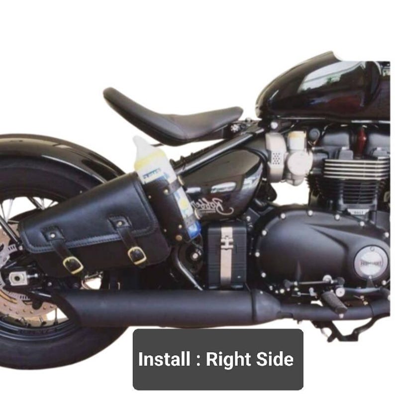 May include: Black leather motorcycle saddlebag with a buckle closure. The saddlebag is attached to the right side of a black motorcycle. The text "Install: Right Side" is visible in the image.