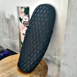 May include: Black quilted motorcycle seat with a diamond pattern.