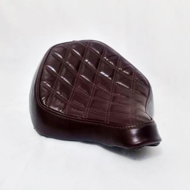 May include: A brown quilted motorcycle seat with a diamond pattern.