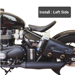 May include: Black leather motorcycle saddlebag with buckles, attached to a black motorcycle. The saddlebag is on the left side of the motorcycle. The text "Install: Left Side" is visible in the image.