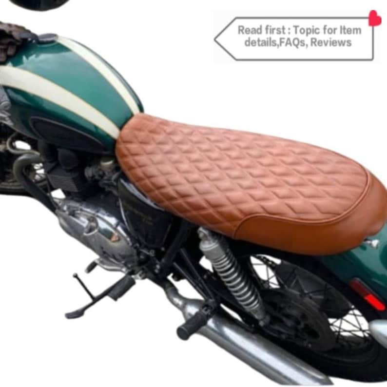 May include: A brown leather motorcycle seat with a diamond pattern. The seat is mounted on a green motorcycle.