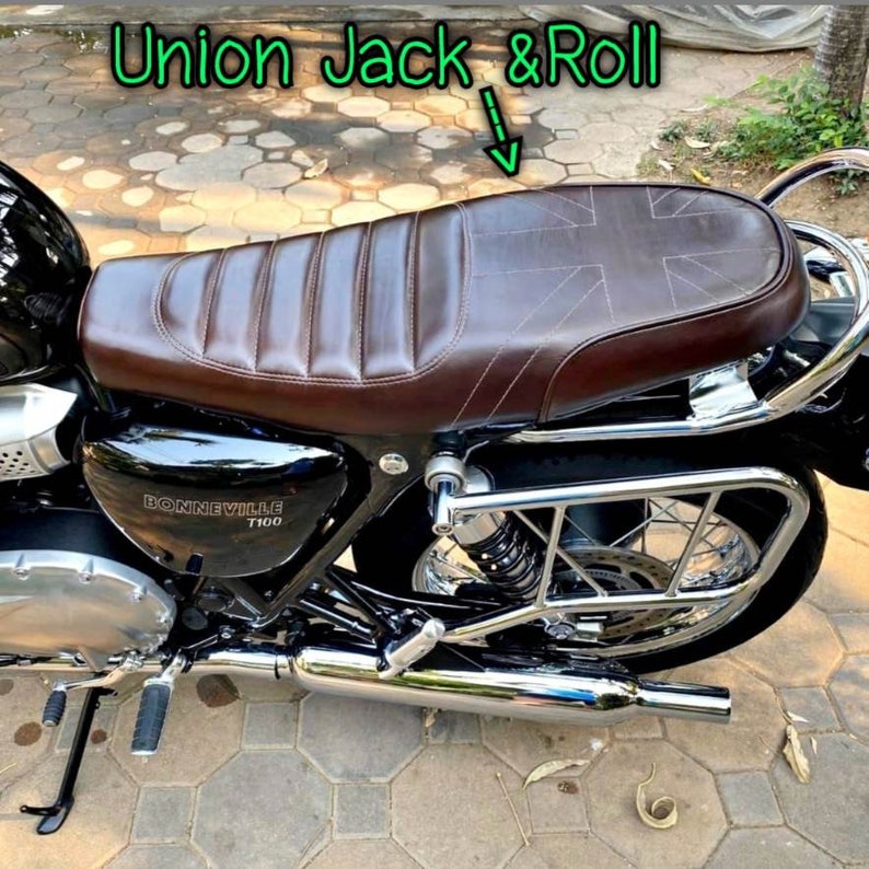 Puede incluir: Un asiento de motocicleta de cuero marr&oacute;n con un dise&ntilde;o de Union Jack cosido en la parte superior. El asiento est&aacute; montado en una motocicleta negra con detalles cromados. La motocicleta tiene un tubo de escape cromado y un portaequipajes cromado.