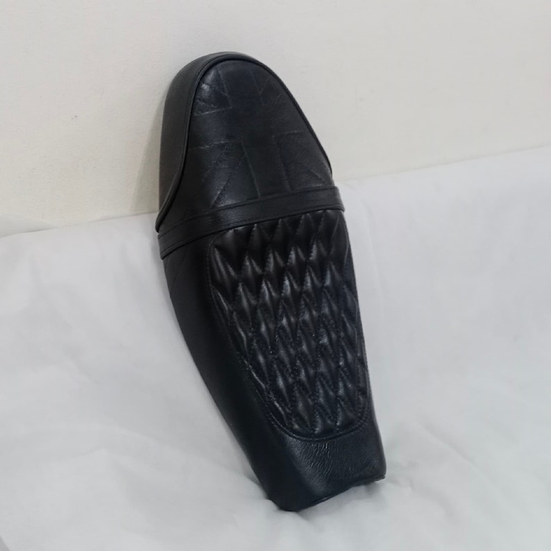 Puede incluir: Asiento de motocicleta de cuero negro con un patr&oacute;n acolchado en forma de diamante y un dise&ntilde;o de Union Jack en la parte posterior.
