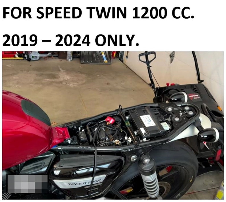 May include: Close-up of a black motorcycle with a red gas tank and a black seat. The motorcycle has a chrome exhaust pipe and a black rear fender. The motorcycle is in a garage and the text "SPEED TWIN" is visible on the side of the motorcycle.