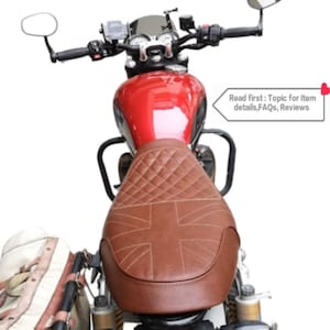 Puede incluir: Un asiento de motocicleta de cuero marr&oacute;n con un patr&oacute;n acolchado y un dise&ntilde;o de Union Jack. El asiento est&aacute; montado en una motocicleta roja.