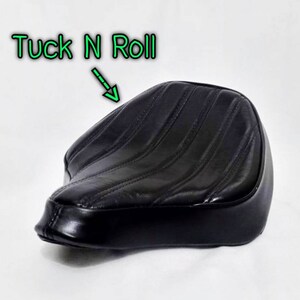 May include: Black leather motorcycle seat with a tuck and roll design. The seat has a stitched pattern and is designed for a solo rider.