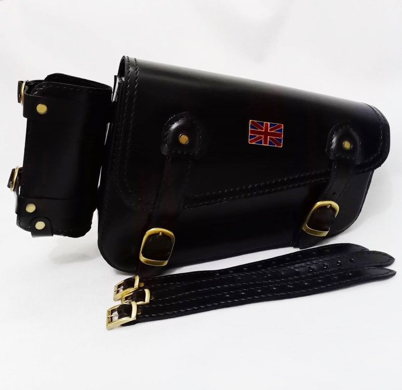 May include: Black leather motorcycle saddlebag with a Union Jack patch, a smaller pouch, and a black leather strap with buckles.