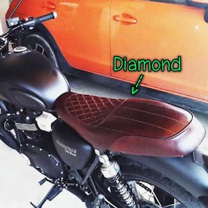 Puede incluir: Un asiento de motocicleta negro con una cubierta de cuero marr&oacute;n con costuras de diamante. El asiento est&aacute; unido a una motocicleta negra con un tubo de escape cromado.