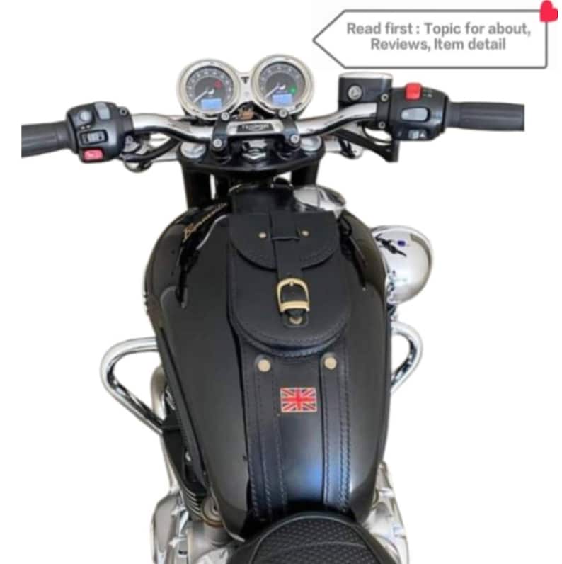 K&ouml;nnte beinhalten: Schwarze Leder-Motorrad-Tanktasche mit einem Union-Jack-Patch und einem Schnallenverschluss. Die Tasche ist an einem schwarzen Motorrad-Benzintank befestigt.