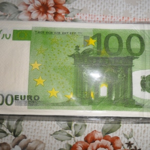 Op de afbeelding: Een 100 eurobiljet gedrukt op een witte papieren servet. Het biljet heeft een groene achtergrond met een gele ster en de tekst "100 EURO".