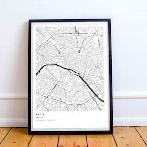 May include: Black and white map print of Paris, France in a black frame. The map shows the streets and landmarks of the city. The text below the map reads "Paris, France 48.8567° N, 2.3522° E."