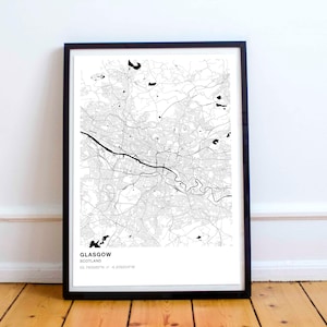 May include: Black and white map print of Glasgow, Scotland, in a black frame. The map shows the city's streets and waterways. The text "GLASGOW, SCOTLAND, 55.8609°N 4.2518°W" is printed at the bottom of the map.