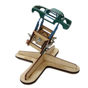 Peut inclure: Un support de construction de modèle de voiture en bois avec une carrosserie verte. Le support est en bois clair et possède une base en forme de croix. La carrosserie est soutenue par des entretoises bleues et du matériel réglable.