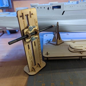 Op de afbeelding: Een houten gereedschap voor het creëren van een gladde, gelijkmatige curve op een scheepsmodel. Het gereedschap heeft een potloodhouder en een schuifmaat. Het gereedschap is gemaakt van licht hout en heeft een natuurlijke afwerking.
