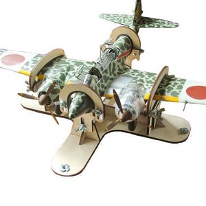 Könnte beinhalten: Ein Modell eines japanischen Mitsubishi G4M Betty Bombers, bemalt in einem Tarnmuster mit roten Kreisen auf den Flügeln, montiert auf einem Holzständer.