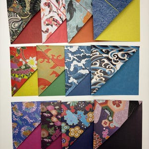 Puede incluir: Una colección de marcapáginas de origami coloridos. Cada marcapáginas presenta un diseño único de inspiración japonesa, incluyendo peces koi, olas y patrones florales. Los marcapáginas son de papel y tienen forma triangular, con un color contrastante en la parte posterior.