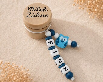 May include: A wooden baby tooth box with the words "Milch Zähne" printed on the lid. Attached is a blue and white beaded pacifier clip with the name "FINN" spelled out and a blue owl charm.