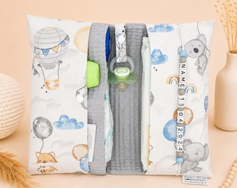 May include: A white and gray baby organizer with a hot air balloon and koala bear pattern. The organizer holds a bottle, pacifier, and diapers. A beaded name tag and the date "15 04 2024" are visible.