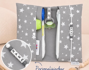 May include: A gray baby changing clutch with a white star pattern. The clutch is open, revealing a bottle, pacifier, diaper, and a personalized name bead. The text "Personalizable" is written on the front.