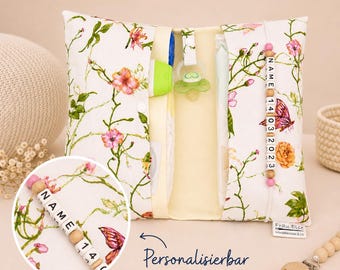 May include: Floral print baby organizer with a pacifier, bottle, and personalized name beads. The organizer features a cream background with pink flowers and green vines. The text "Personalizable" is visible.