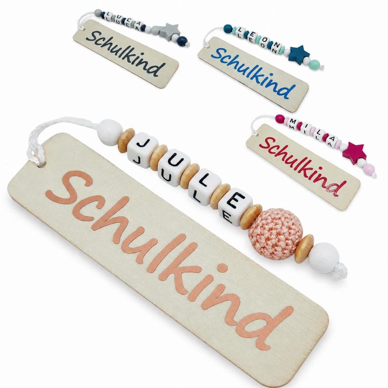 May include: Wooden bookmarks with the word "Schulkind" printed in various colors. Each bookmark has a beaded charm with a name spelled out in letter beads. The charms include star and round beads.