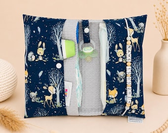 May include: A navy blue baby changing clutch with a woodland animal print. The clutch is open, revealing a pacifier, diaper, and other baby essentials. A wooden bead strand with the name and date is attached.